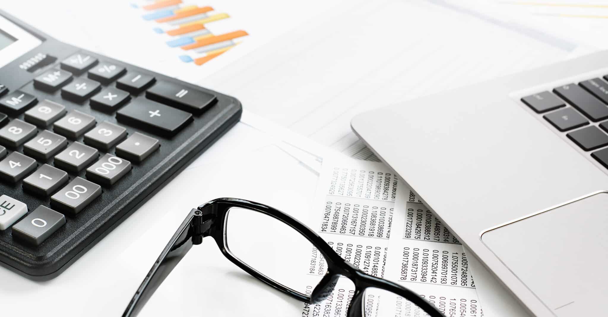 calculator, glasses and laptop on a table
