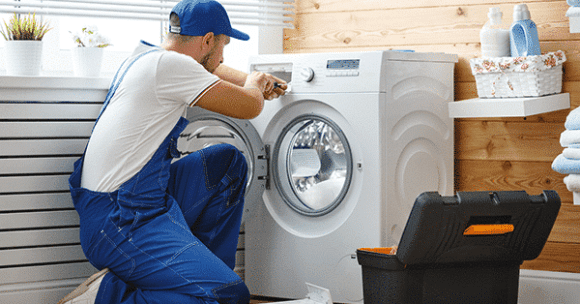 Technician kneeling working on a washer machine