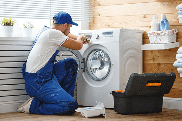 Technician kneeling working on a washer machine