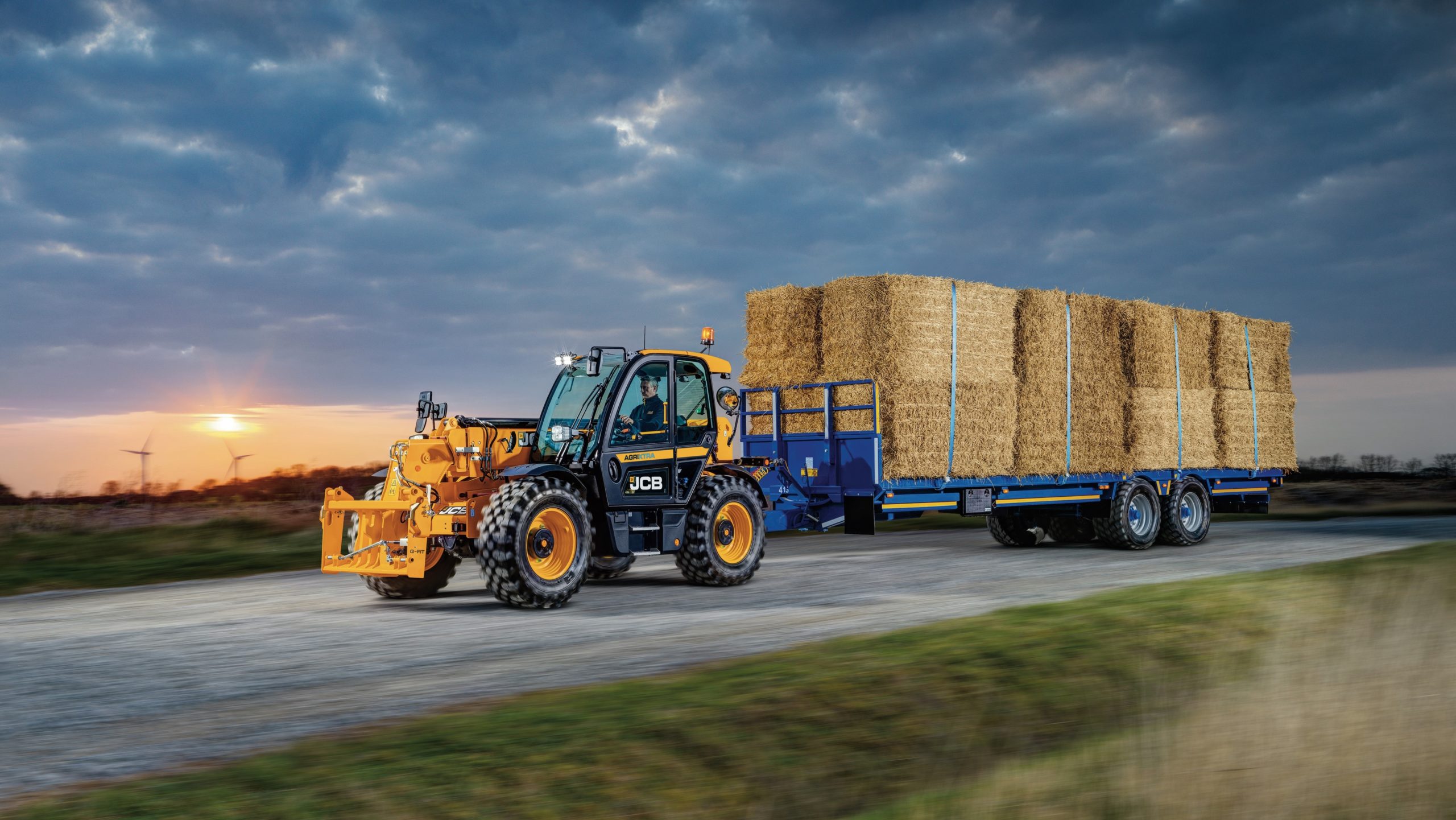 JCB equipment pulling trailor of hay
