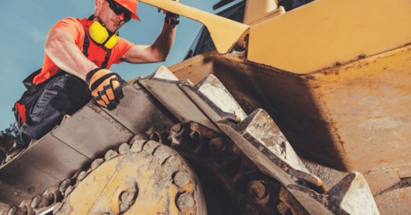 Technician working on track of construction equipment