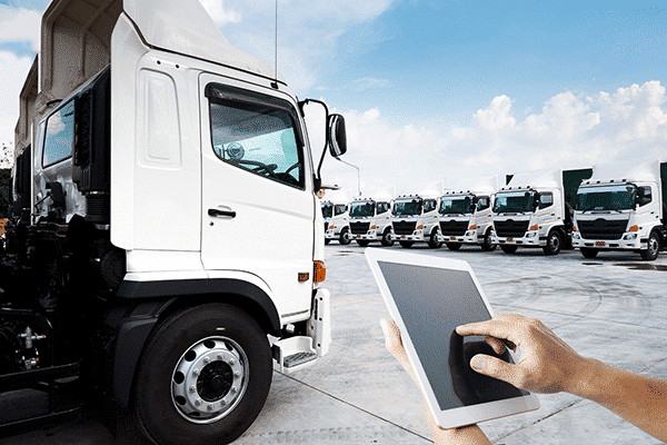 Holding tablet in front of parked PACCAR trucks