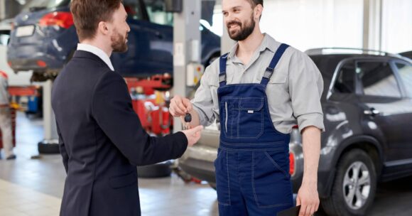 Technician handing customer keys to his car