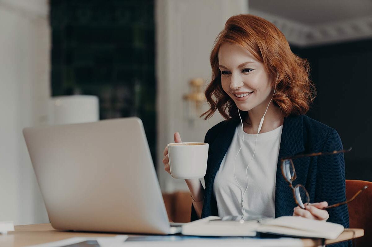 Girl working on laptop and coffee in hand