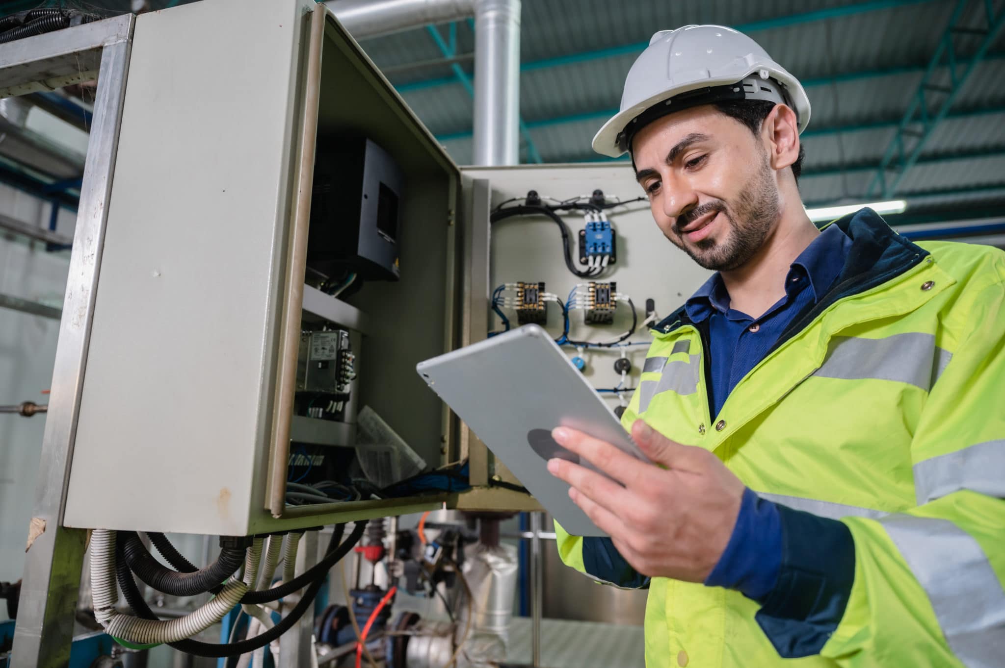 Technician reading tablet in front of electronics box