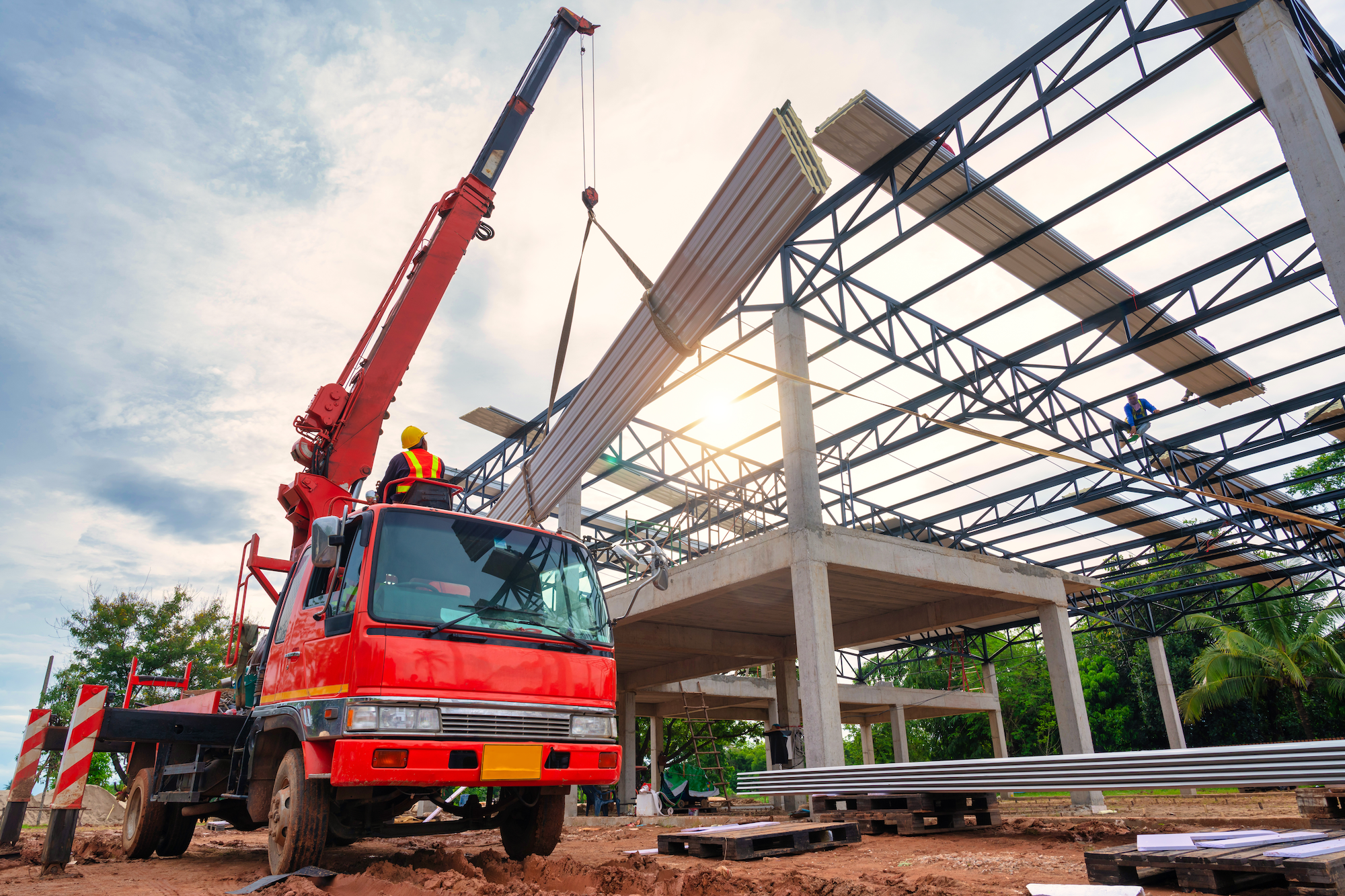 large red truck with cane lifting panels onto a large structure