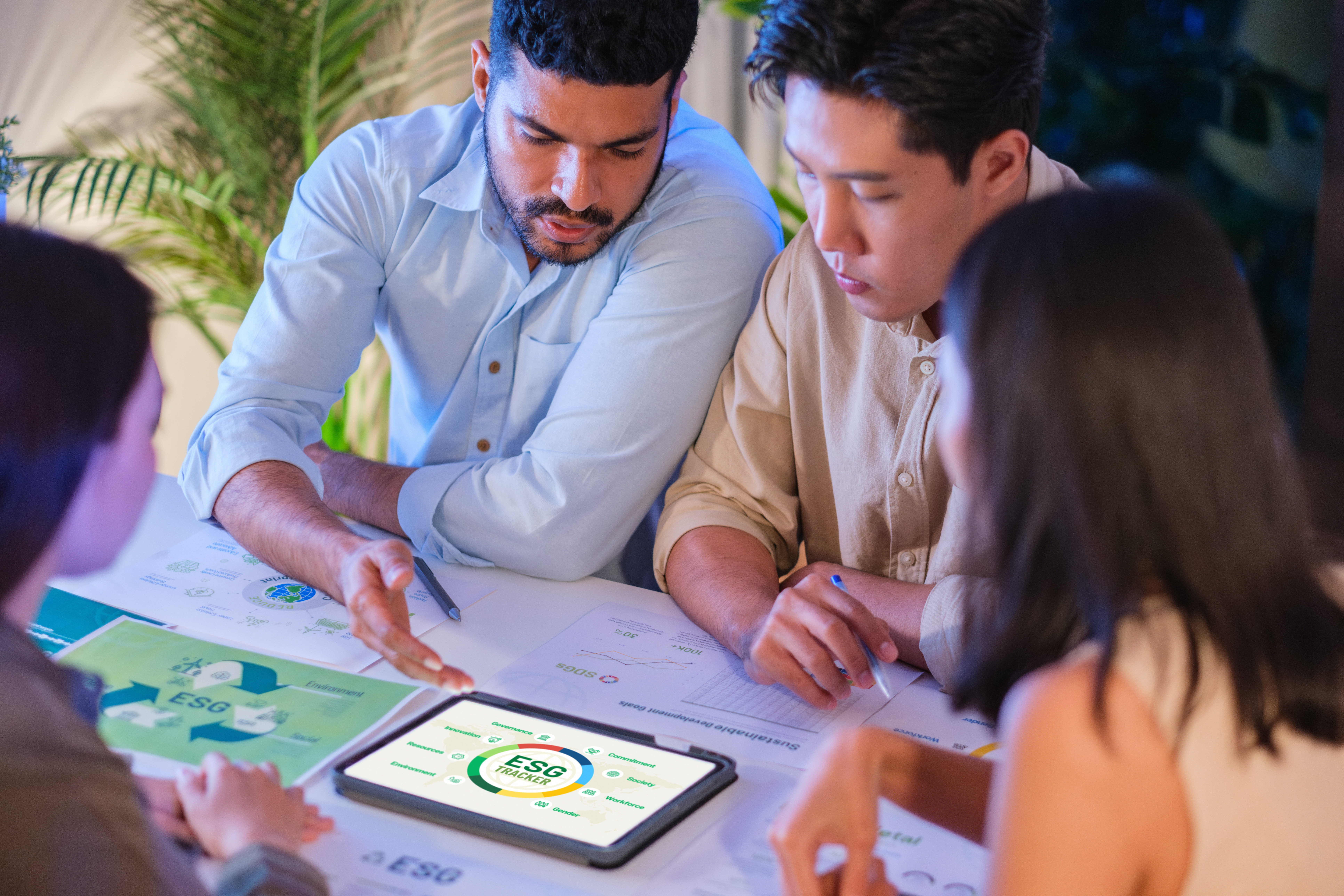 diversity team brainstorming focused on ESG (environment,social,governance) with tablet or sdgs goals in a sustainable green office at night