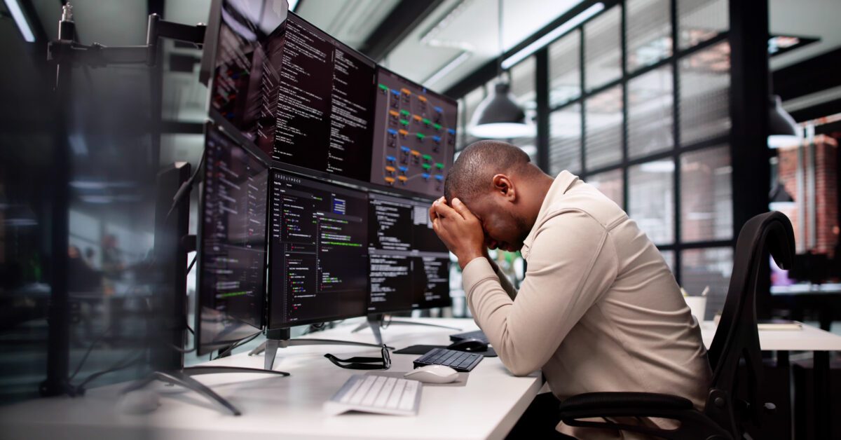 A man with multiple monitors frustrated with data