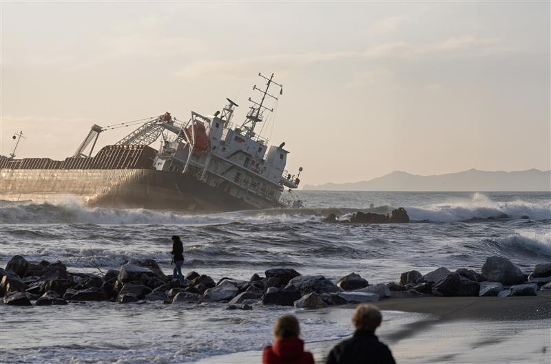 cargo ship crashing into shoreline with people watching